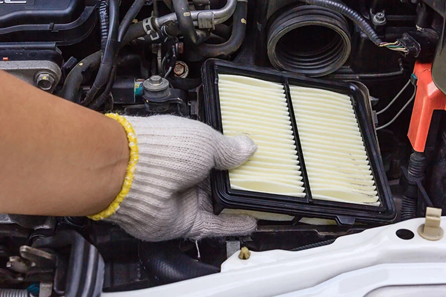 A GMC professional is replacing an air filter with a white-gloved hand